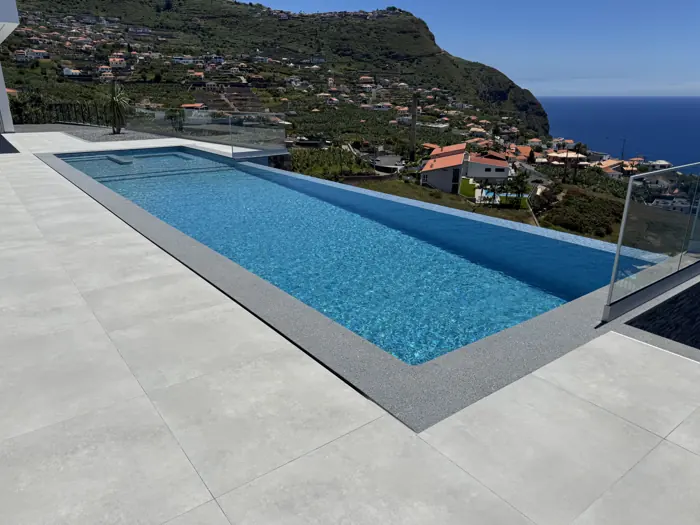 Swimming pool of Elysium Calheta with the green coast and the ocean of Madeira behind it